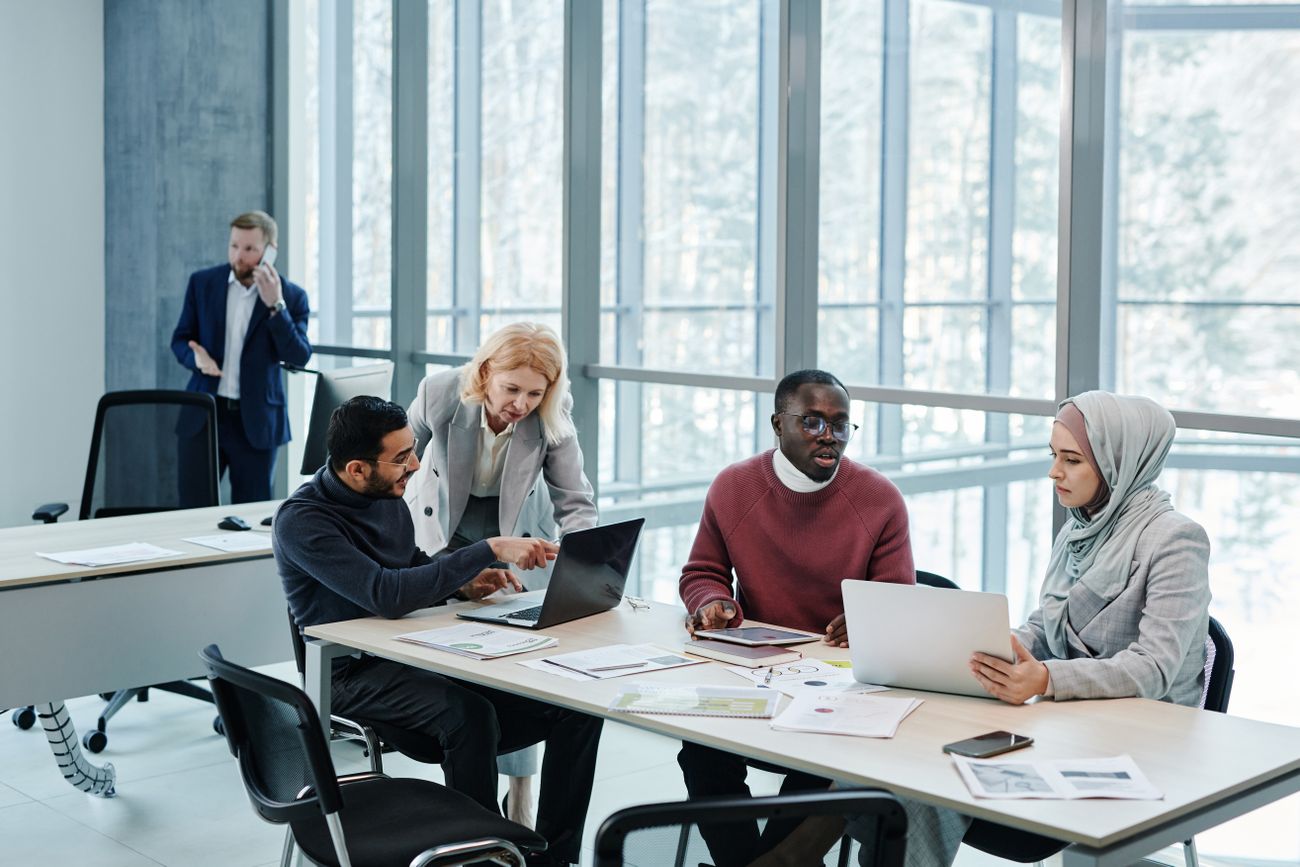 A team working at a long table by tall windows