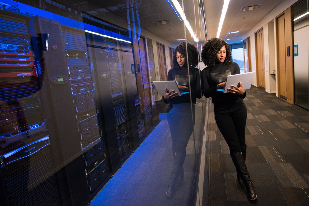An engineer with a laptop beside server racks