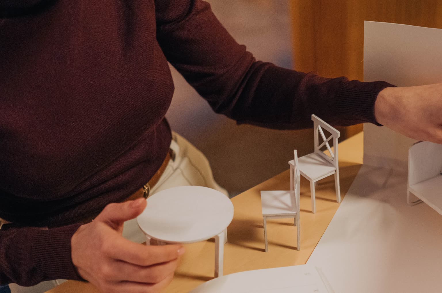 Architect setting paper furniture into a white study model