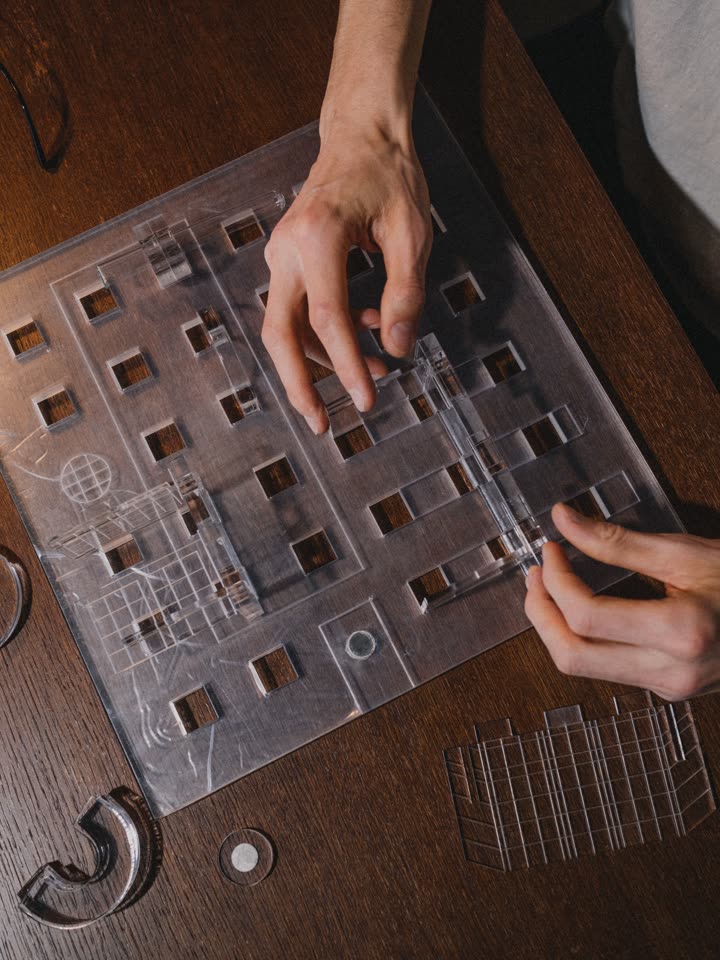 Hands fitting clear acrylic layers of a facade model