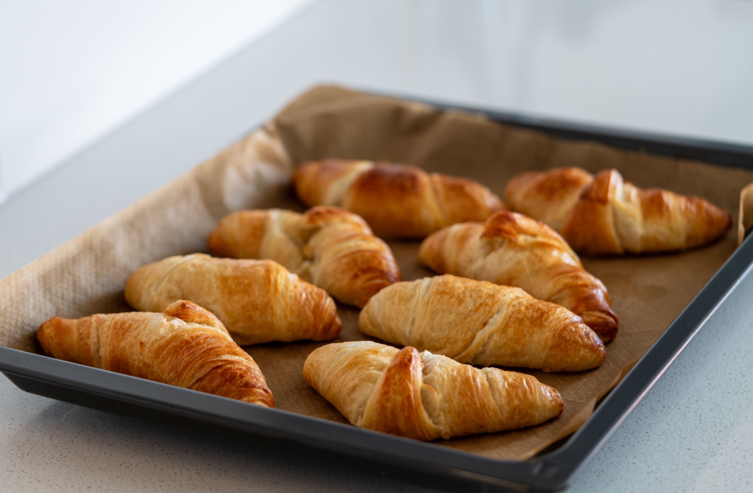 Butter croissants on a parchment-lined sheet tray, fresh from the oven