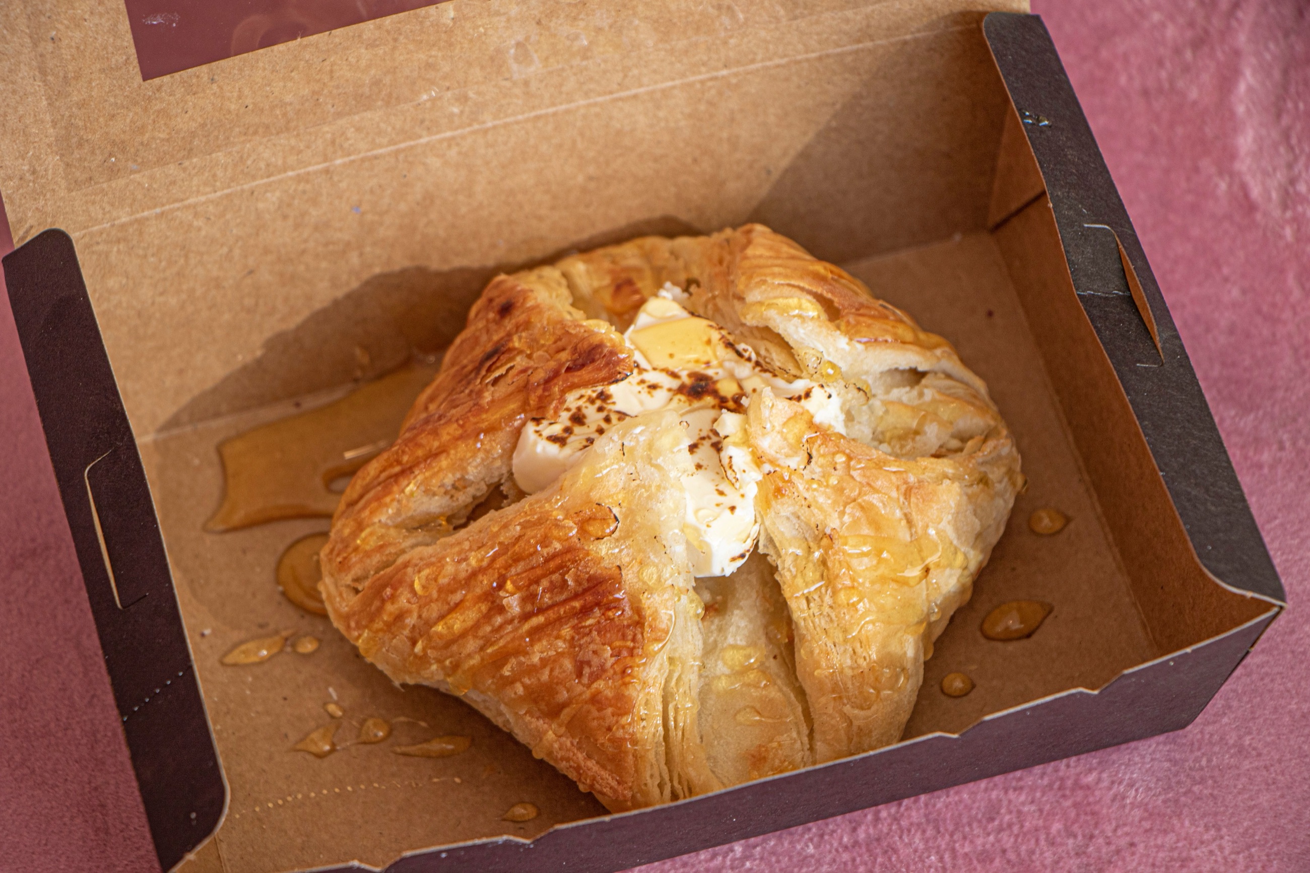 A honey-glazed pastry in a kraft bakery box
