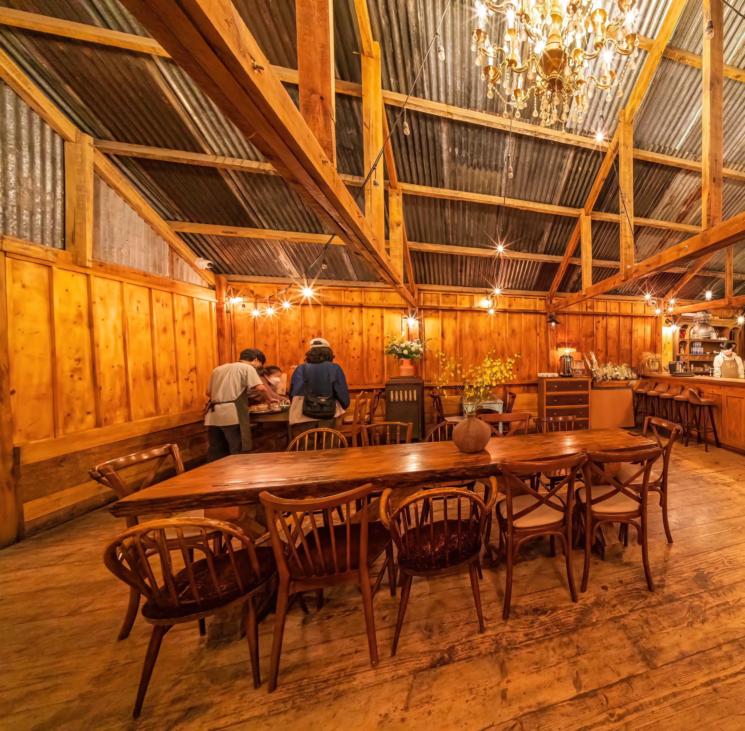 The long shared table in the dining room under the timber roof