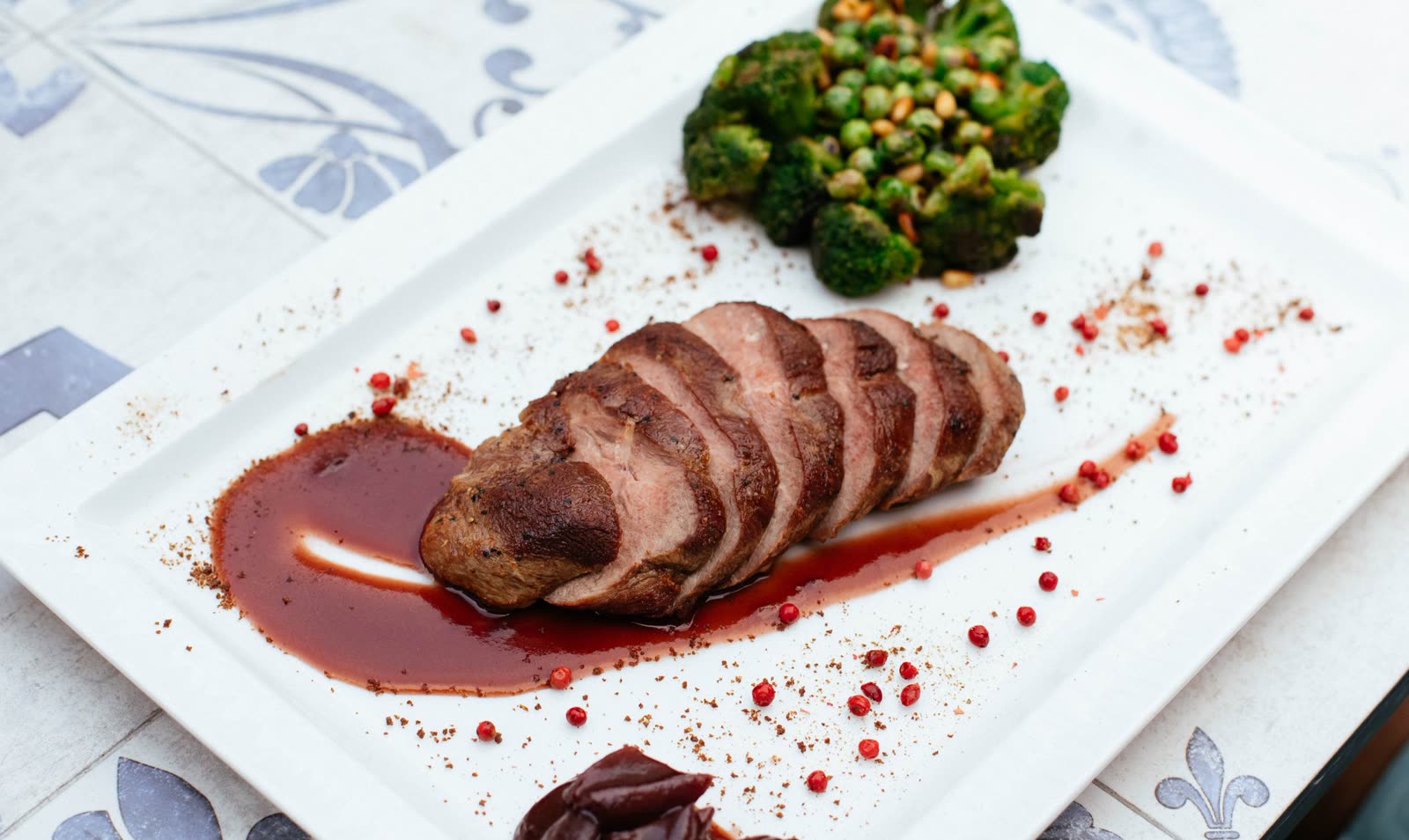 Duck leg braised in red wine with pearl onions in a yellow-rimmed bowl