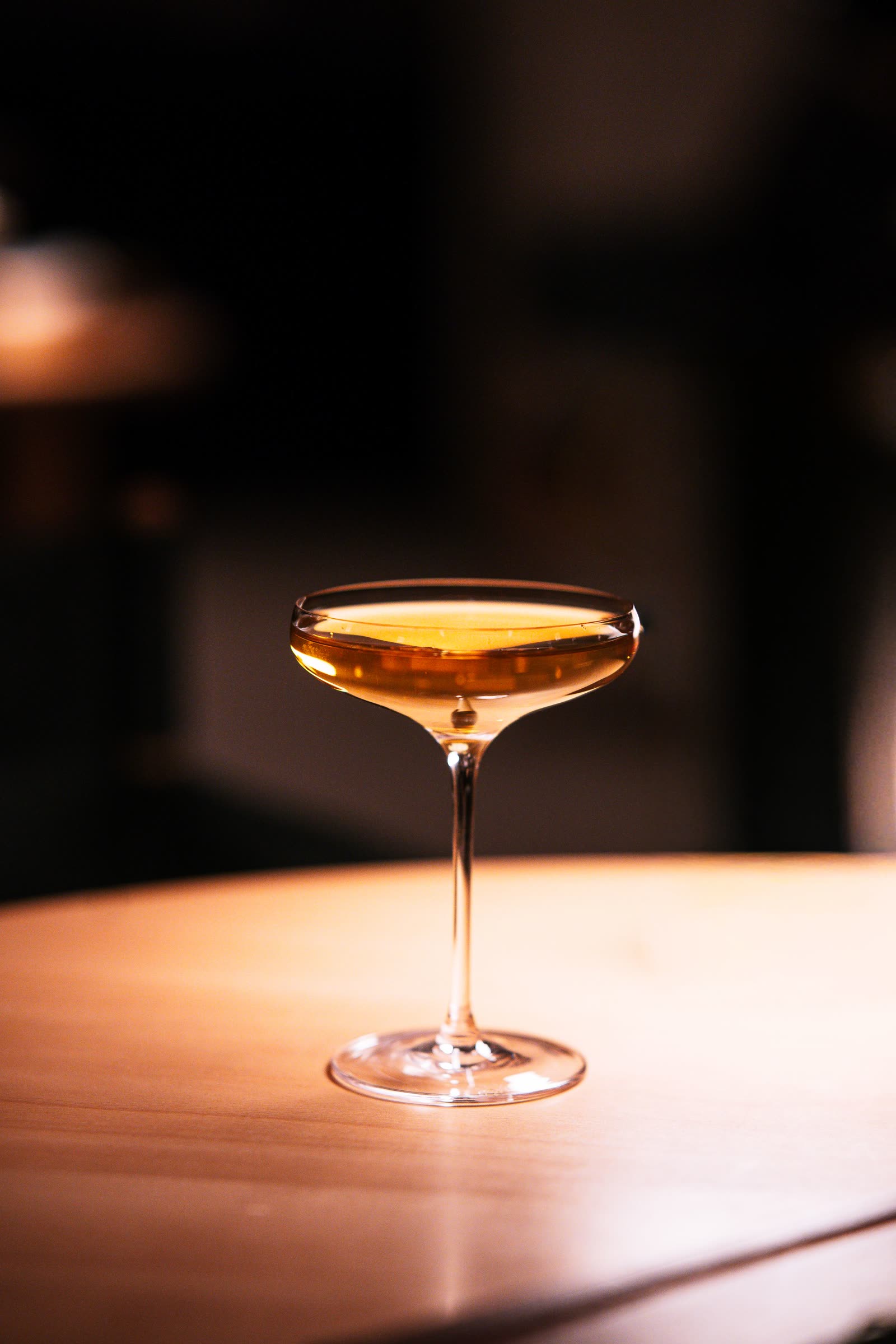 A coupe cocktail held up in the candlelight