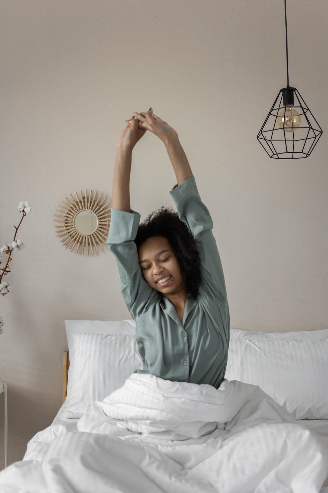 A woman stretching her arms overhead in bed