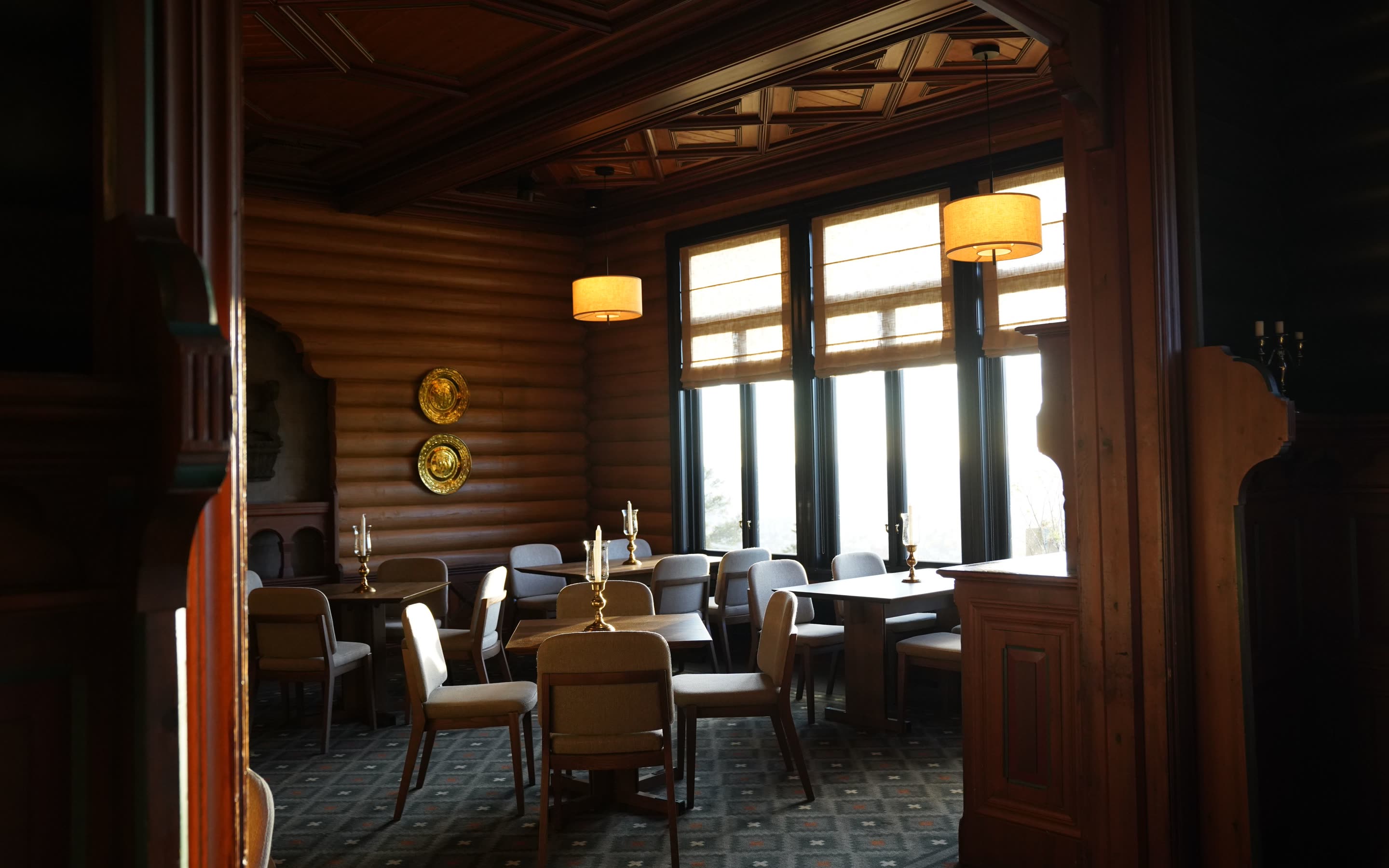 Log-walled dining room with lamps and tall windows