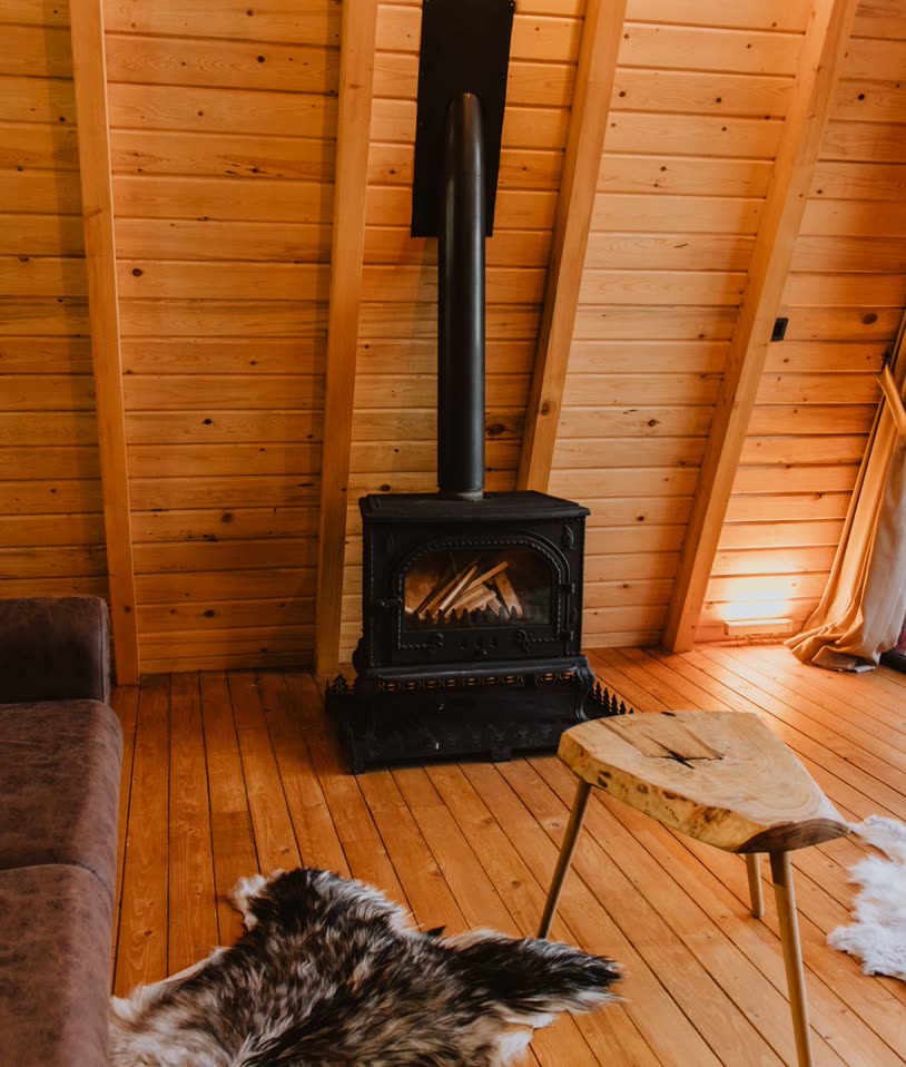 Cast-iron wood stove in a pine-panelled room with a slab side table