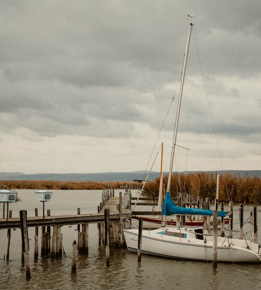 A small sailboat moored at a wooden pier