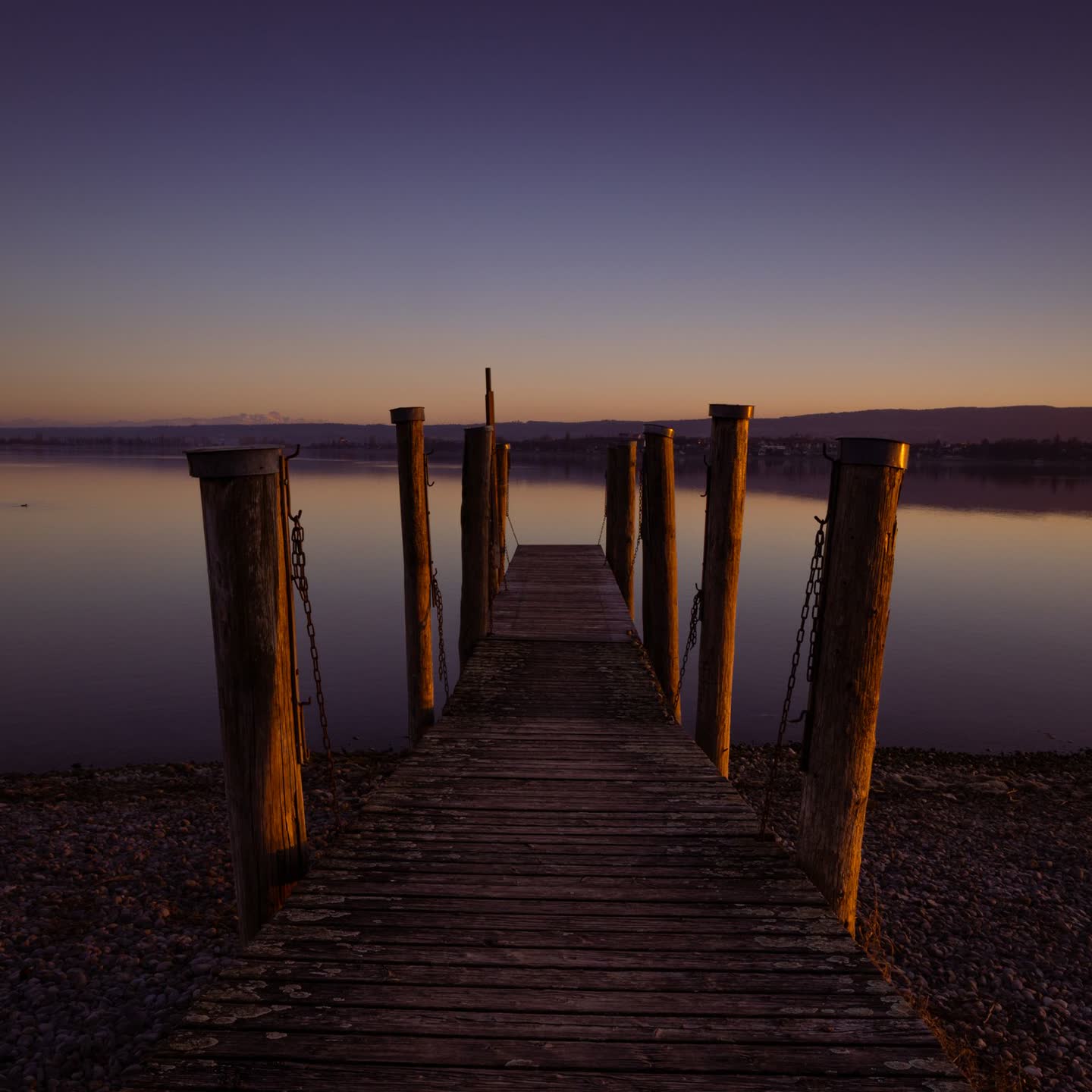 Weathered pier posts leading out to the lake at dusk
