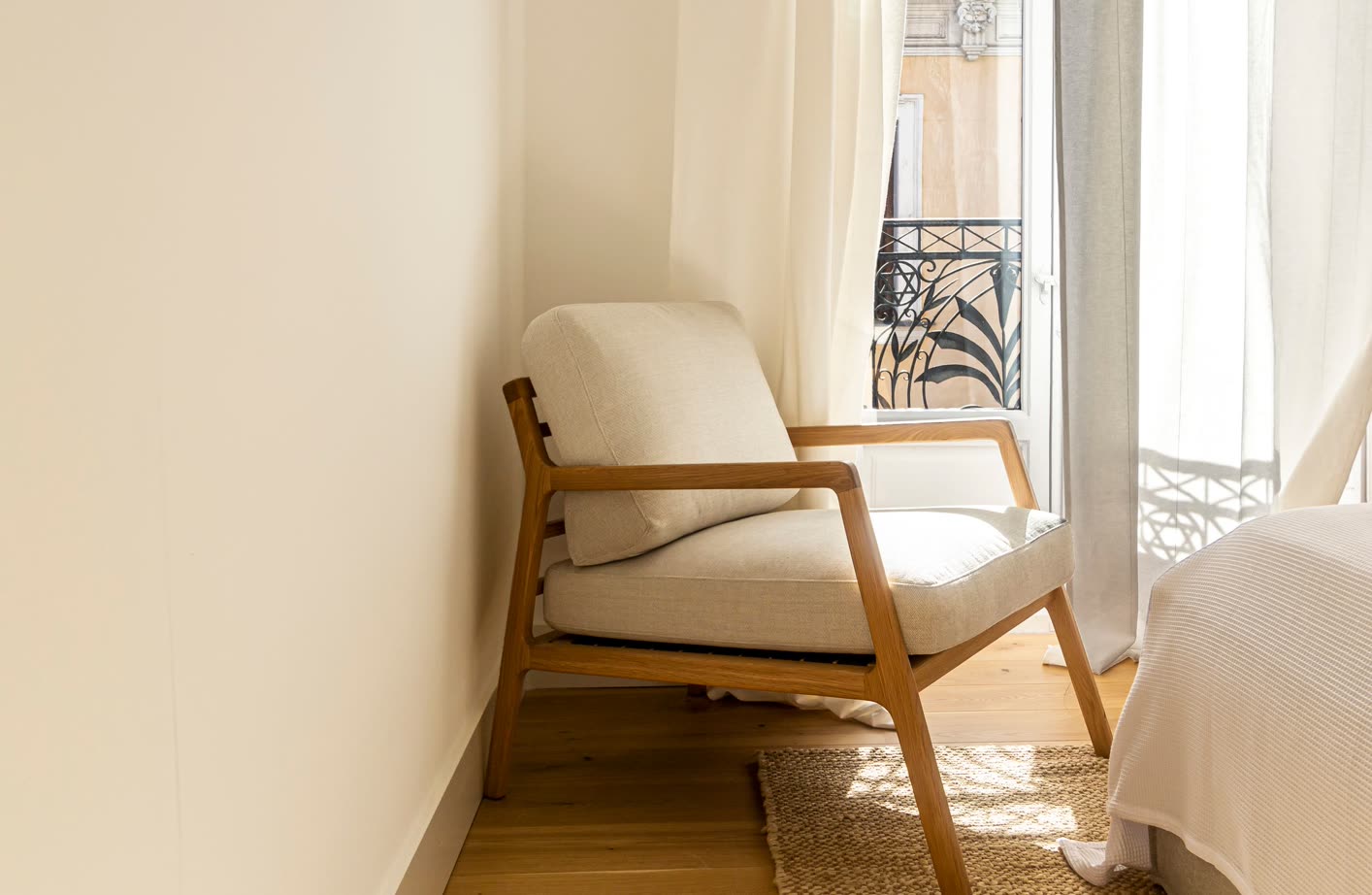 A cushioned wooden armchair in a sunny corner by the window
