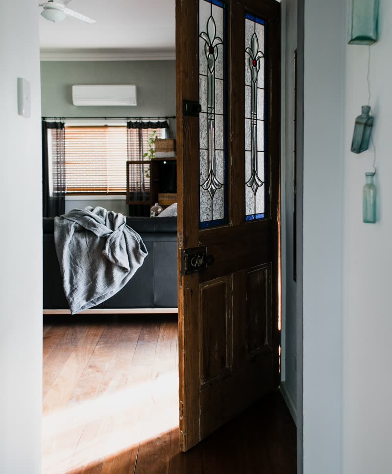 A wooden door standing open onto a sunlit sitting room