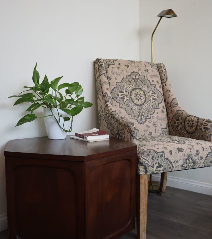 A patterned armchair beside a reading lamp and a side table