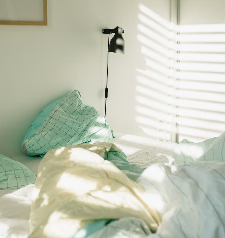 Morning light across an unmade bed