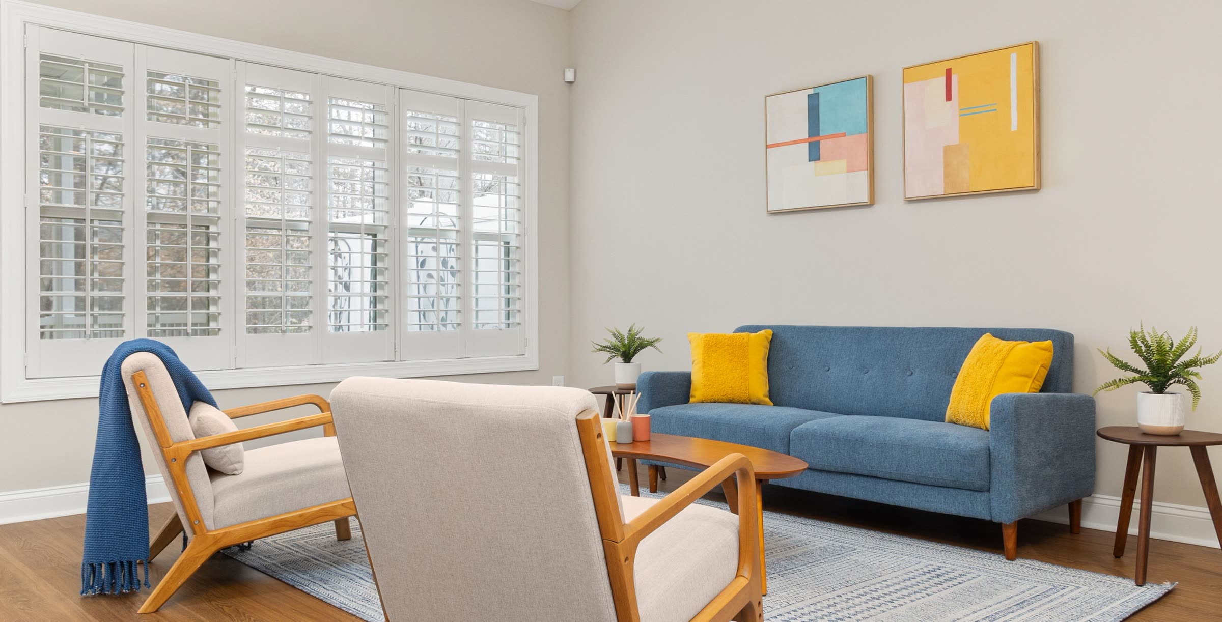 A counseling room with two wooden armchairs, a blue sofa and window shutters