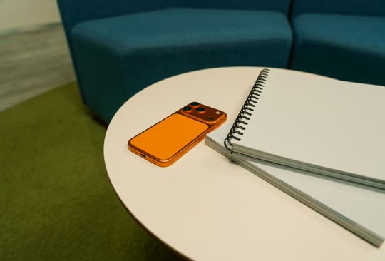 A phone and a spiral notebook on a round table