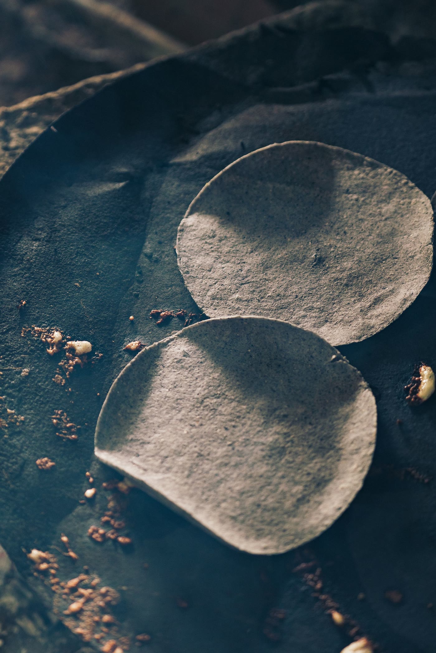 Two blue corn tortillas on a dark comal